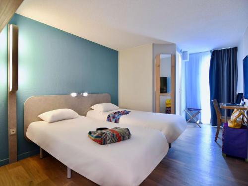 Cette chambre d'hôtel comprend 2 lits avec des draps blancs. dans l'établissement ibis budget Vannes, à Vannes