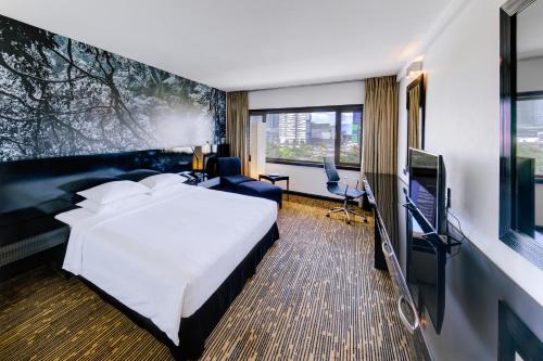 um quarto de hotel com uma cama e uma televisão de ecrã plano em Cinnamon Lakeside em Colombo