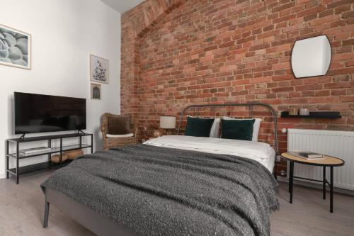 um quarto com uma cama e uma parede de tijolos em HARBOR APARTMENTS - Damrota em Katowice