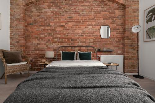 een slaapkamer met een bed en een bakstenen muur bij HARBOR APARTMENTS - Damrota in Katowice