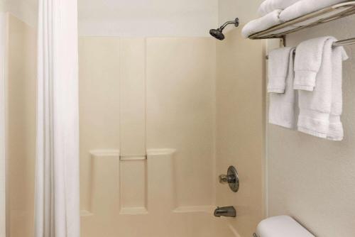 a bathroom with a shower with a toilet and towels at Baymont by Wyndham Cedar Rapids in Cedar Rapids