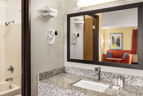 a bathroom with a sink and a mirror at Baymont by Wyndham Cedar Rapids in Cedar Rapids