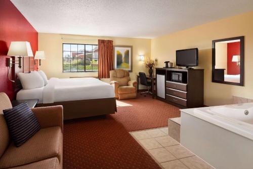 シーダーラピッズにあるBaymont by Wyndham Cedar Rapidsのベッドとバスタブ付きのホテルルームです。