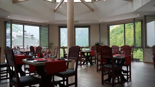 a dining room with tables and chairs and windows at Havila Hotel Geiranger in Geiranger