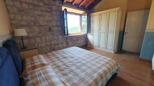 1 dormitorio con cama y pared de piedra en La Bandita Cottage, en San Venanzo