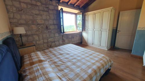 une chambre avec un lit et un mur en pierre dans l'établissement La Bandita Cottage, à San Venanzo