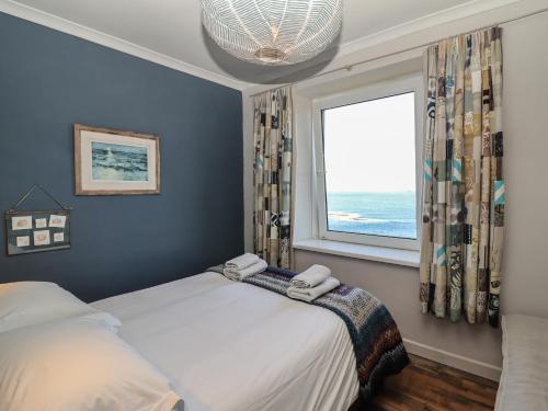 1 dormitorio con 2 camas y ventana en Starfish, en Penzance