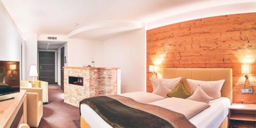 a bedroom with a large bed and a fireplace at Hotel Eibl-Brunner 4-Sterne-Superior in Frauenau