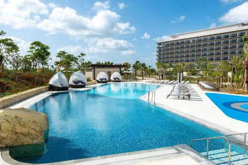 uma piscina no resort com um hotel ao fundo em Hilton Okinawa Miyako Island Resort em Ilhas Miyako