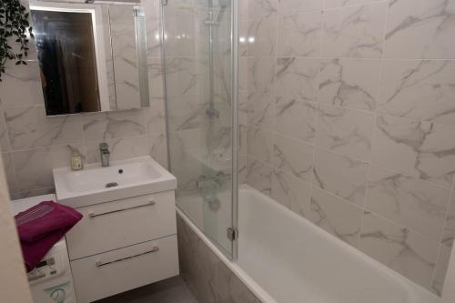 ein weißes Bad mit einer Dusche und einem Waschbecken in der Unterkunft Stade de France 6 pers in Saint-Denis