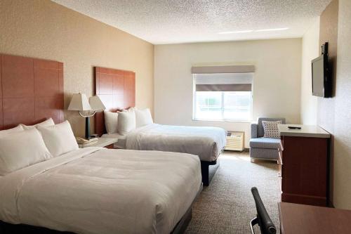 a hotel room with two beds and a chair at AmericInn by Wyndham Grinnell in Grinnell