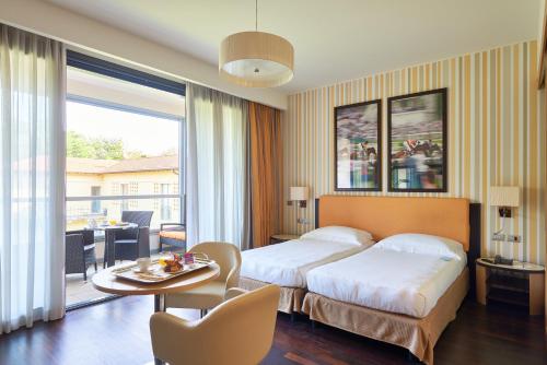 a hotel room with two beds and a table at UNAHOTELS Varese in Varese