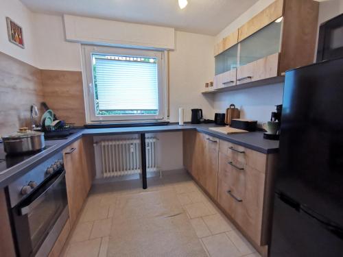 a kitchen with wooden cabinets and a black refrigerator at 3 Zimmer-Apartment mit Terrasse in Gernsbach