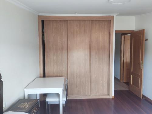 a room with a desk and a wooden closet at Habitación doble en Salceda de Caselas in Parderrubias