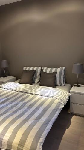 a bed with striped sheets and pillows in a bedroom at Casa Polizzi - Maison entière in Fontaine-lʼÉvêque