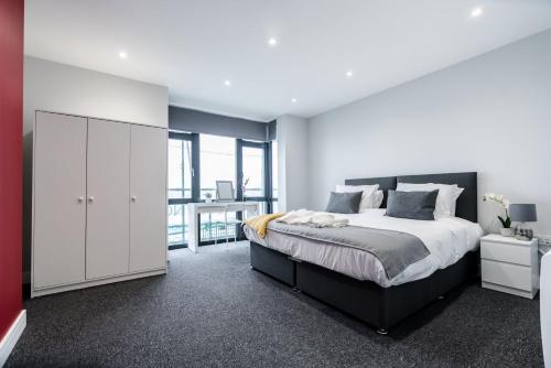 a bedroom with a large bed with white cabinets at K Suites - Colne House in Lowestoft