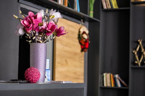 eine Vase voller rosa Blumen auf dem Tisch in der Unterkunft R34 Boutique Guest House in Weliko Tarnowo
