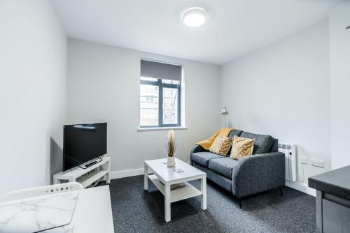a living room with a couch and a tv at K Suites - Colne House in Lowestoft