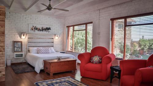 1 dormitorio con 1 cama y 2 sillas rojas en The Owl House, en Jeffreys Bay