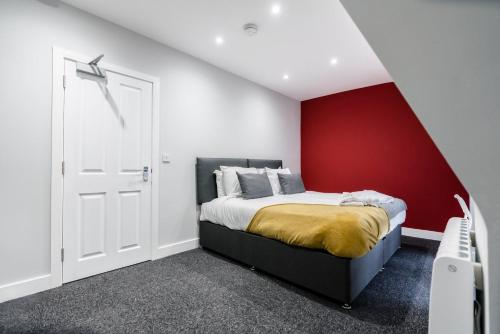 a bedroom with a bed with a red accent wall at K Suites - Colne House in Lowestoft