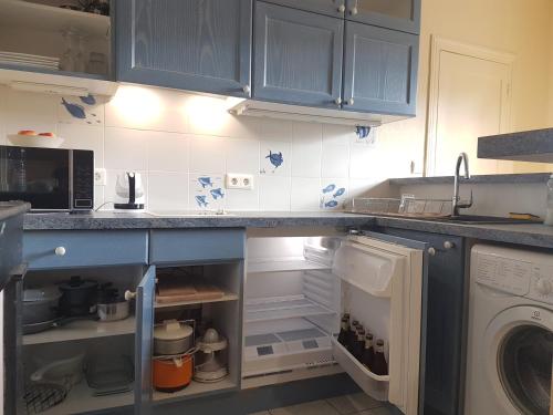 - une cuisine avec des placards bleus et un lave-linge/sèche-linge dans l'établissement Studio près de la tour Eiffel, à Paris
