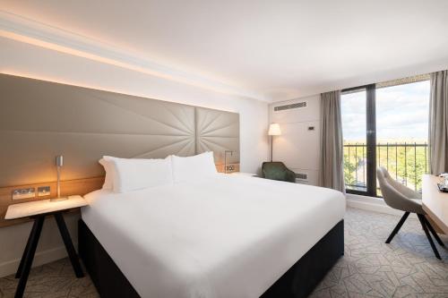 a large white bed in a hotel room with a window at Hilton Birmingham Metropole Hotel in Bickenhill