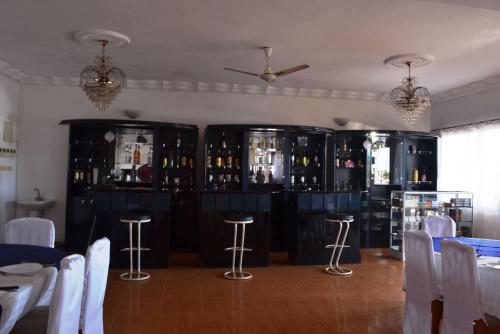um quarto com um bar com armários pretos e bancos em Austral Hotel em Farafangana