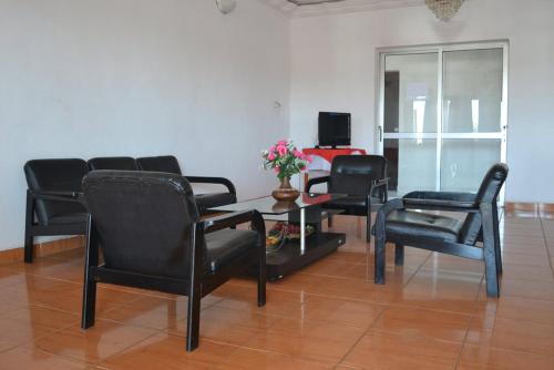 uma sala de espera com cadeiras pretas e uma mesa com flores em Austral Hotel em Farafangana