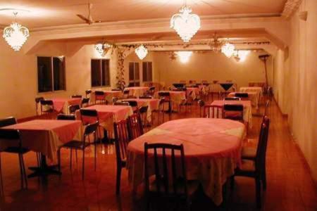 uma sala de jantar com mesas, cadeiras e lustres em Austral Hotel em Farafangana