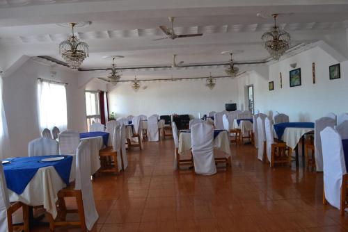 uma sala cheia de mesas e cadeiras com toalhas de mesa azuis e brancas em Austral Hotel em Farafangana