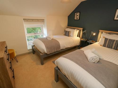 a bedroom with two beds and a window at Flora Cottage in Buxton