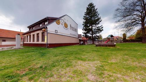 a building with a playground in a grass field at Penzion Pod kolem in Šošŭvka