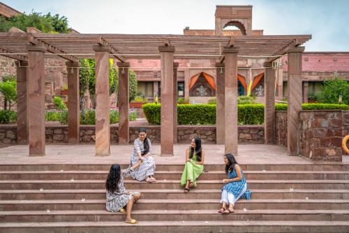 vier Frauen sitzen auf der Treppe vor einem Gebäude in der Unterkunft The Hosteller Heritage Palace, Jodhpur in Jodhpur