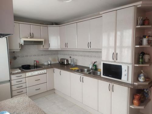 a kitchen with white cabinets and a sink and a microwave at Habitacion Privada Triple Toledo in Toledo