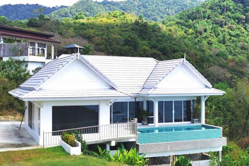 a white house with a pool in front of a mountain at BaanKuer Hill Pool Villa in Ko Lanta