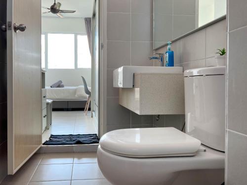 a white bathroom with a toilet and a sink at Seaview Private Master Bedroom in a Shared Unit in Tanjong Tokong