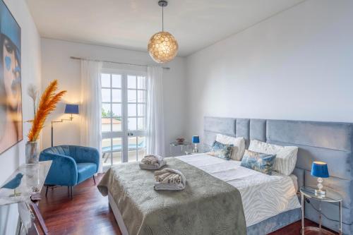 1 dormitorio con 1 cama grande y 1 silla azul en VILLA LEONARDO, en Caniço