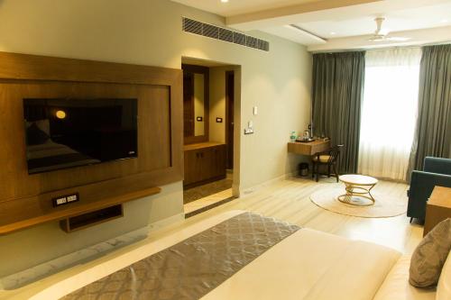 a living room with a bed and a flat screen tv at Hotel Westend in Udaipur