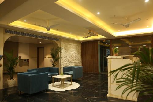a lobby with blue couches and a table and plants at Hotel Westend in Udaipur