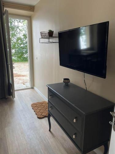 - une commode noire avec une télévision murale à écran plat dans l'établissement Studio au bord de l'eau, à Saint-Seurin-de-Bourg