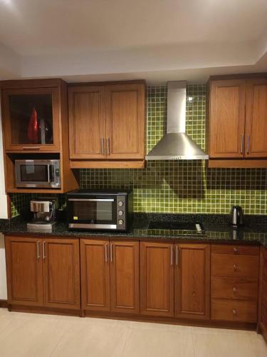 a kitchen with wooden cabinets and a microwave at Khanom Beach Residence Monthly Rental Condo in Khanom