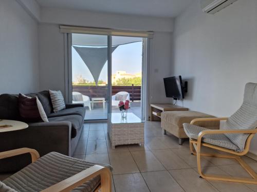 a living room with a couch and chairs and a tv at Kalifi Pool Apartment in Paralimni