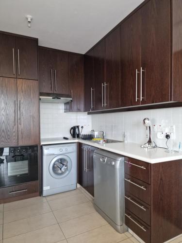 a kitchen with wooden cabinets and a washer and dryer at Kalifi Pool Apartment in Paralimni
