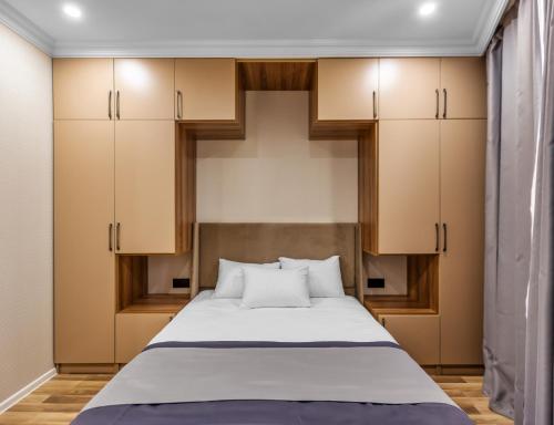um quarto com uma grande cama branca e armários em Hillside City Center Hotel em Baku