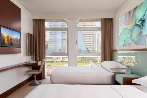 a hotel room with two beds and a large window at Villa Rotana in Dubai