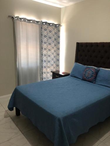 a bedroom with a blue bed and a window at Lovely 2 BedRoom c̅ Netflix across National Stadium Kingston in Kingston