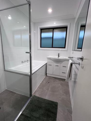a bathroom with a shower and a tub and a sink at Kangaroo Island Homestays in Kingscote