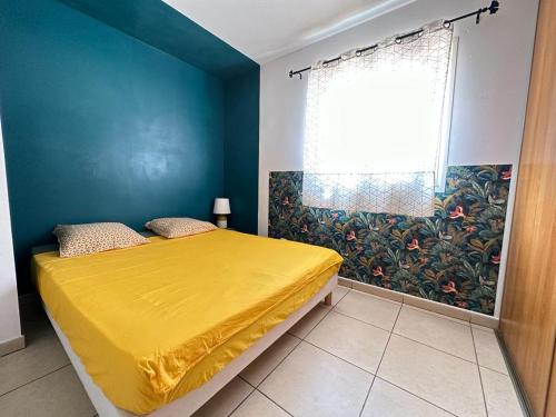 sypialnia z żółtym łóżkiem i oknem w obiekcie Appartement T3 proche aéroport et Nordev w mieście Sainte-Clotilde