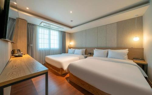 釜山的住宿－Adena Hotel，酒店客房设有两张床和窗户。