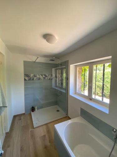 La salle de bains est pourvue d'une baignoire blanche et d'une fenêtre. dans l'établissement Villa provençale familiale avec piscine, à Grimaud